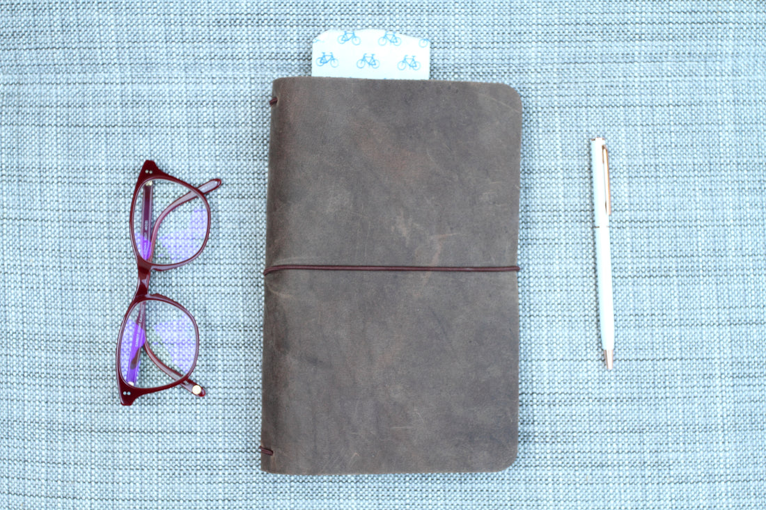 brown leather traveler's notebook, refillable leather journal, red glasses and pen